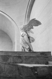 Monochrome image of Winged Victory of Samothrace statue in Paris's Louvre Museum.