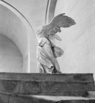 Monochrome image of Winged Victory of Samothrace statue in Paris's Louvre Museum.